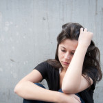 photo of a young distressed woman sitting on the ground contemplating with her head resting in her arm - breakaway hired power - understanding alcoholics and addicts