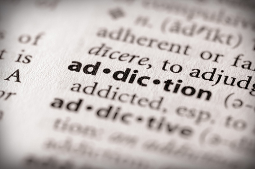 photo of a dictionary focused on the word addiction and the word addictive is below it out of focus - addictive personality - hired power breakaway