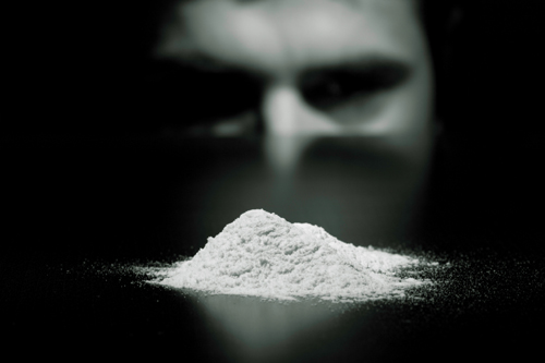 photo of cocaine addicted individual staring at a pile of cocaine - focus on cocaine - breakaway hired power - cocaine nose bleed
