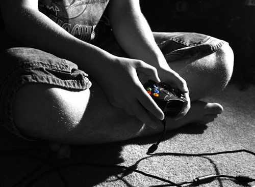 photo of a person holding a game controller in his lap, photo is in black and white with the game controller in color - gaming addiction - hired power breakaway