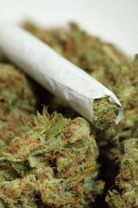 Image of a marijuana cigarette on top of loose substance
