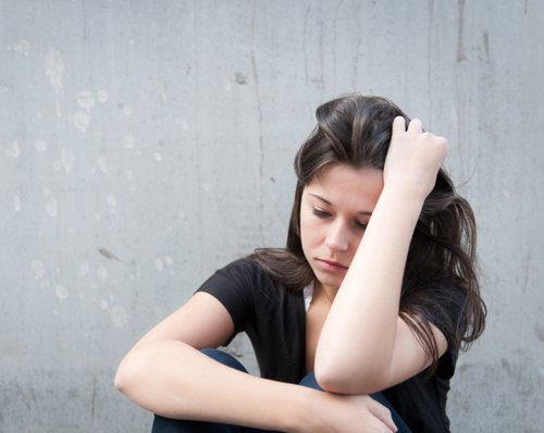 photo of a young distressed woman sitting on the ground contemplating with her head resting in her arm - breakaway hired power - understanding alcoholics and drug addicts